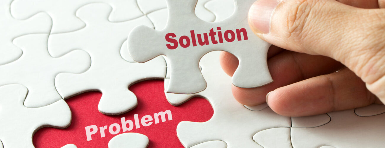 Hand putting last piece of puzzle with the word solution to fix the problem